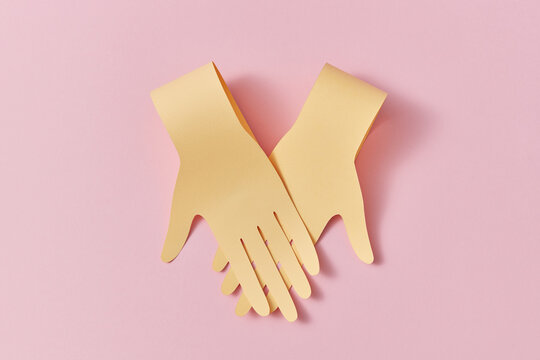 Two crossing paper handmade hands.