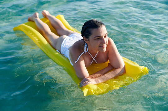 Smiling woman lying on float on the ocean
