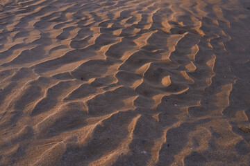 Textura de arena blanca en la playa formada por las olas del mar al atardecer. pequeñas dunas de arena blanca formadas por el océano al bajar la marea 