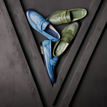 Two pairs of colored Italian handmade leather shoes on a black background