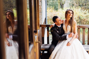 bride in wedding dress sits with groom in uniform on bench near
