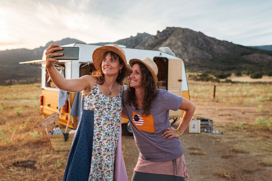Happy small business owners taking selfie near van