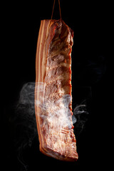 Bacon in smoke on dark background.