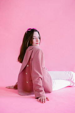 the girl sits in a pink jacket worn on the contrary