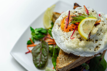 Egg in a cloud on grilled sandwiches with cumberland sausage, tomato and mayonnaise, all served with a fresh salad