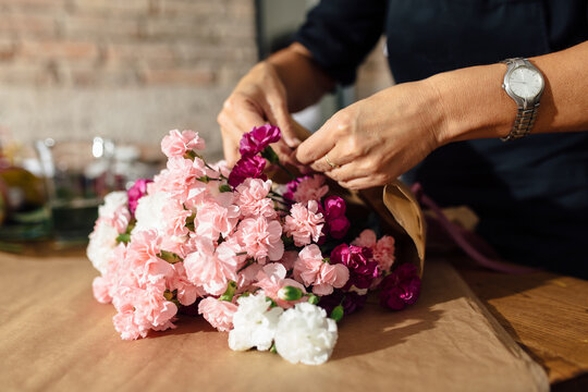 Anonymous Woman Wrapping Flower Bouquet In Kraft Paper