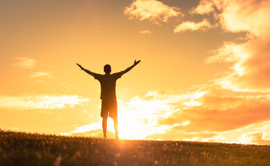 Silhouette of happy man in a nature setting with hands up to the sunset sky. Happiness, and hope concept. 