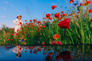 beautiful girl posing in a field of poppies on a background of b