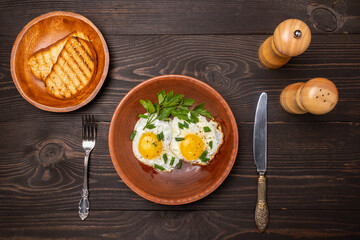 fried eggs with herbs on a clay plate top view