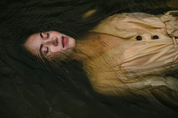 beautiful young eyes woman lies in water with closed