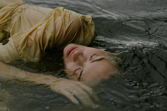 beautiful young eyes woman lies in water with closed
