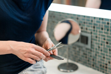A woman gives herself a haircut at home.