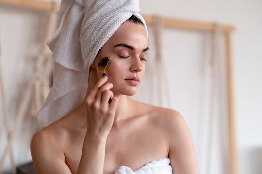 A Woman Using A Facial Roller