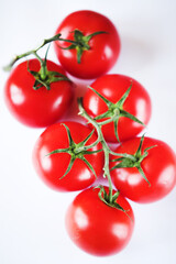 Red tomatoes on a green twig on white background