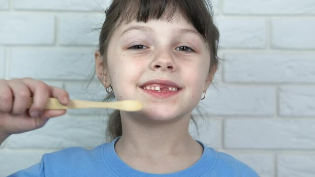 Morning ritual with teeth brush. A child show her morning ritual with a bamboo teethbrush in the room.
