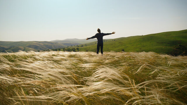 The guy enjoys the wind in the feather grass field.