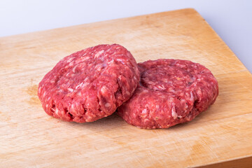 Two Fresh Raw Beef Burgers on Wooden Cutting Board close-up