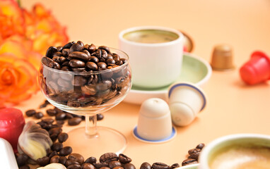 Capsules for an espresso machine . Aromatic Italian coffee in a cup and a bouquet of roses . Arabica coffee beans for the preparation of a traditional drink . High quality photo. Copy space