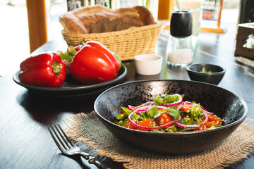 Quinoa salad with tomatoes, avocado, paprika and parsley on black stone plate.