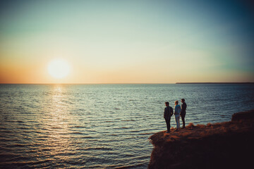 The three people standing on the mountain top near the sea