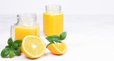 Orange juice and green leaves on a white background.A glass of orange juice and orange fruit. Healthy food. Vegan food. Diet and proper nutrition. Copy space. Place for text.