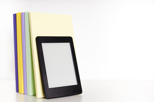 Books with blank spine and electronic reader on a white shelf, white background