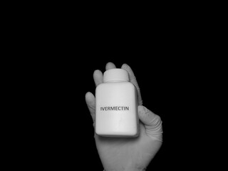 Healthcare worker holding bottle with ivermectin pills, treatment of covid 19