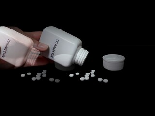 Human hand spill ivermectin pills on black table, covid 19 treatment