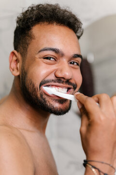 Cheerful ethnic guy brushing teeth