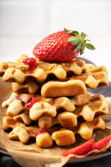 Waffles with strawberries and nut paste on the plate. Delicious dessert. White background. Macro. Front view. Selective focus. 