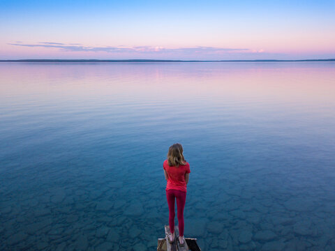 Teen Girl Enjoying Dusk at Family Cottage on Small Dock at the Lake
