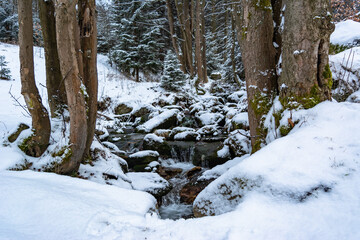 Frozen waterfall cascading over ice and snow covered rocks