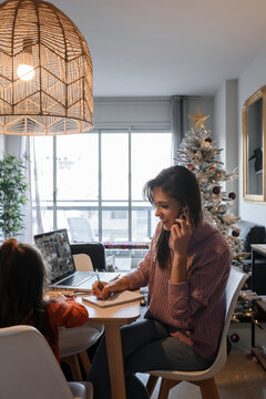 Female freelancer working near daughter before Christmas