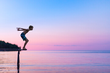 Boy About to Jump into Calm Lake at Dusk from a Dock at Family Cottage