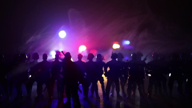 Anti-riot police give signal to be ready. Government power concept. Spec ops police in action. Smoke on a dark background with lights. Blue red flashing sirens. Selective focus