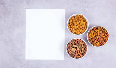Diet for animals. Bowls with cat food copy space. Blank sheet of paper and dry food