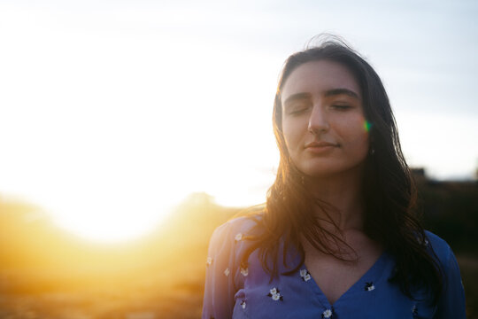 Young soulful woman with eyes closed at sunset