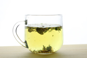 Glass cup with herbal tea on wooden table with white background