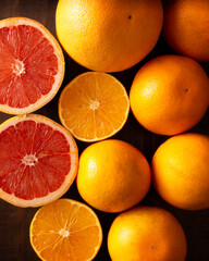 top view image of ripe orange and grapefruit slices and several whole oranges on brown rustic wooden table