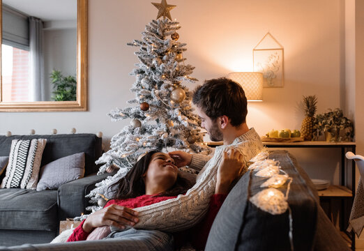 Happy diverse couple lounging on couch on Christmas eve