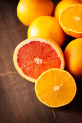 ripe orange and grapefruit slices and several whole oranges on brown rustic wooden table with copy space