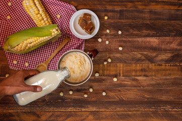 Mazamorra cup with panela pieces, milk bottle and cobs over rustic wood table. Top of view of typical colombian drink, latin food concept. Copy space