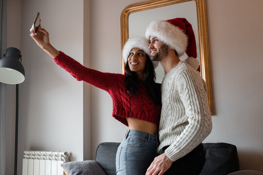 Happy multiethnic couple taking selfie on Christmas Day