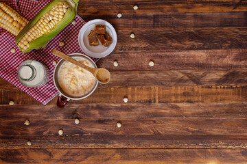 Mazamorra cup with panela pieces, milk bottle and cobs over rustic wood table. Top of view of typical colombian drink, latin food concept. Copy space