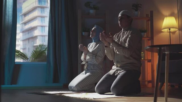 muslim couple joint prayer at home in traditional clothing