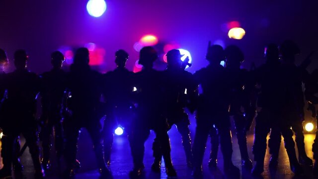 Anti-riot police give signal to be ready. Government power concept. Spec ops police in action. Smoke on a dark background with lights. Blue red flashing sirens. Selective focus