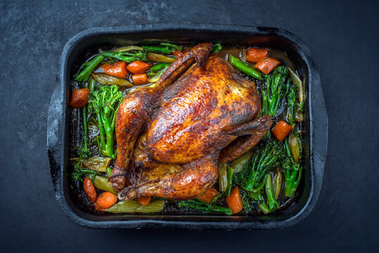 Traditional barbecue chicken with baby broccoli and carrots served as top view in an old rustic metal tray