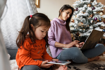 Girl using tablet near busy mother