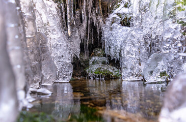 Obraz na płótnie Canvas Waterfall in winter. Water jets freeze and icicles form. Attractive ice shapes and white frost - like a theater stage and impressive winter sets