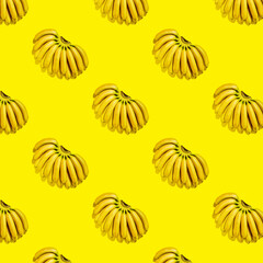 Pattern of small ripe yellow bananas on bright yellow background. Fruit background summer tropical pattern